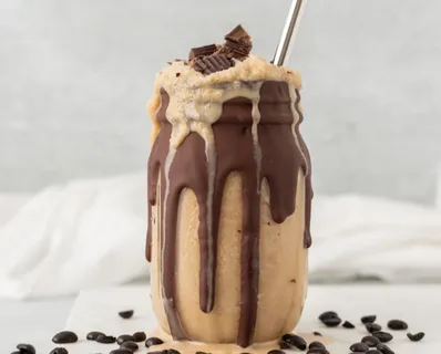 Creamy iced coffee in a jar with chocolate drizzle and toppings.